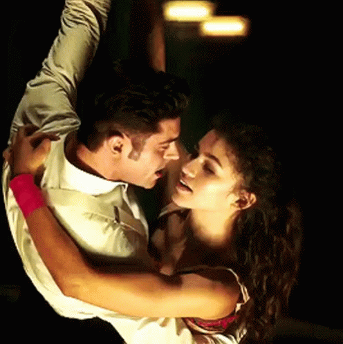 A Man And A Woman Are Dancing And The Woman Has A Pink Wristband GIF