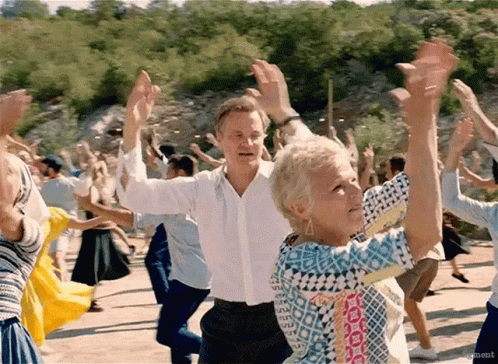 A Man And A Woman Are Dancing In A Crowd With Their Arms In The Air . GIF