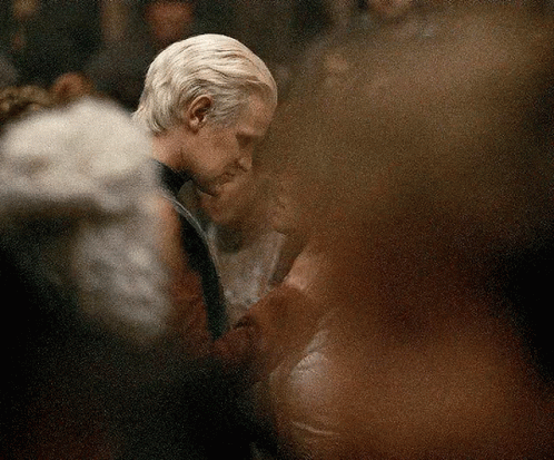 A Man And A Woman Are Dancing In A Crowded Room . GIF
