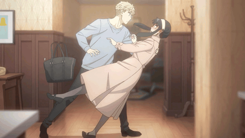 A Man And A Woman Are Dancing In A Hallway With A Purse GIF