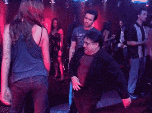 A Man And A Woman Are Dancing In A Nightclub . GIF