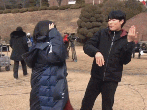 A Man And A Woman Are Dancing In A Park GIF