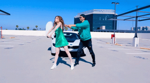 A Man And A Woman Are Dancing In A Parking Lot GIF