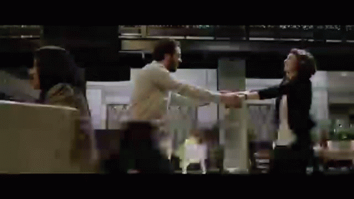 A Man And A Woman Are Dancing In A Room While A Woman Looks On . GIF