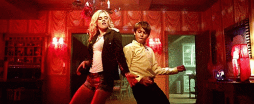 A Man And A Woman Are Dancing In A Room With Red Walls . GIF
