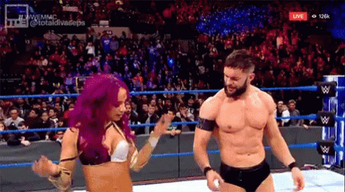 A Man And A Woman Are Dancing In A Wrestling Ring While A Crowd Watches . GIF