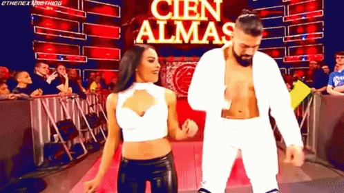 A Man And A Woman Are Dancing In Front Of A Banner That Says Cien Almas GIF