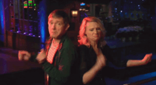 A Man And A Woman Are Dancing In Front Of A Building GIF