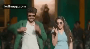 A Man And A Woman Are Dancing In Front Of A Crowd . GIF