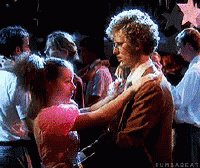 A Man And A Woman Are Dancing In Front Of A Crowd Of People . GIF