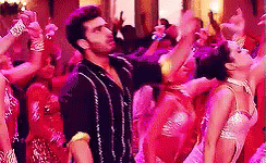A Man And A Woman Are Dancing In Front Of A Crowd Of People . GIF