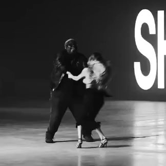 A Man And A Woman Are Dancing In Front Of A Large S GIF