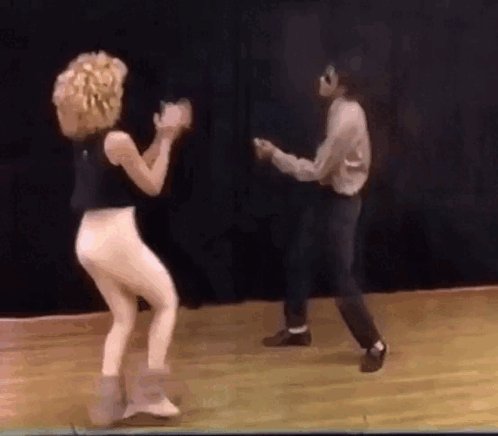 A Man And A Woman Are Dancing On A Stage . GIF
