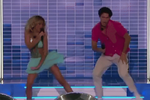 A Man And A Woman Are Dancing On A Stage In Front Of A Tiled Wall . GIF
