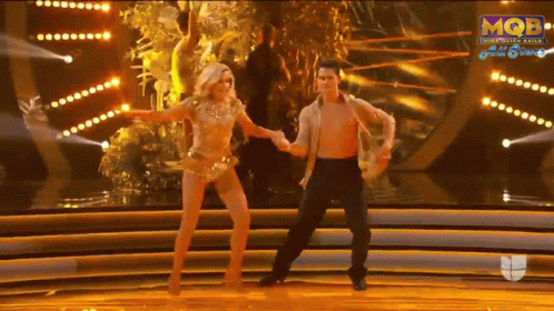 A Man And A Woman Are Dancing On A Stage With A Mqb Logo In The Background GIF