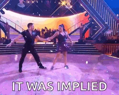 A Man And A Woman Are Dancing On A Stage With The Words It Was Implied Above Them GIF