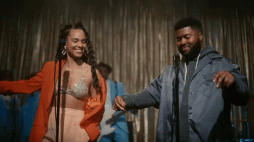 A Man And A Woman Are Dancing On Stage In Front Of A Microphone GIF