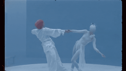 A Man And A Woman Are Dancing Together In A Blue Room GIF
