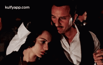A Man And A Woman Are Dancing Together In A Dark Room In A Movie . GIF