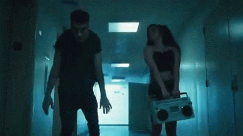 A Man And A Woman Are Dancing Together In A Hallway In A Dark Room . GIF