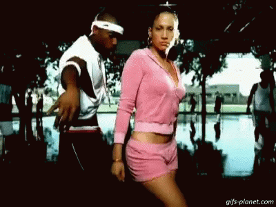 A Man And A Woman Are Dancing Together In A Park . The Woman Is Wearing Pink Shorts And A Pink Sweater . GIF