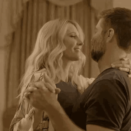 A Man And A Woman Are Dancing Together In A Room In A Sepia Tone . GIF