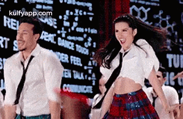 A Man And A Woman Are Dancing Together On A Stage In Front Of A Large Screen . GIF