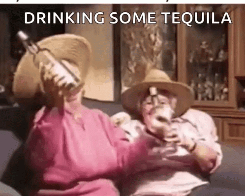 A Man And A Woman Are Drinking Tequila On A Couch . GIF