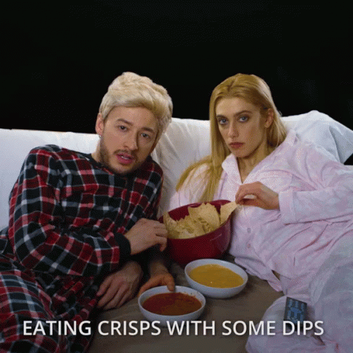 A Man And A Woman Are Eating Crisps With Dips GIF