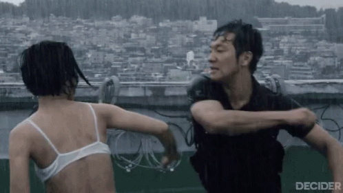 A Man And A Woman Are Fighting In The Rain . The Woman Is Wearing A White Bra . GIF