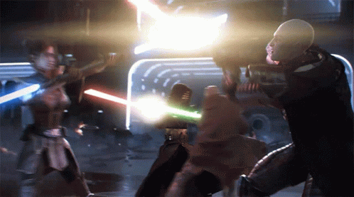 A Man And A Woman Are Fighting With Lightsabers In A Dark Room GIF