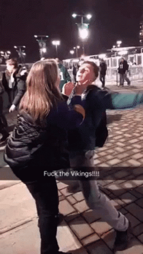 A Man And A Woman Are Fighting With The Words Fuck The Vikings On The Bottom Right GIF