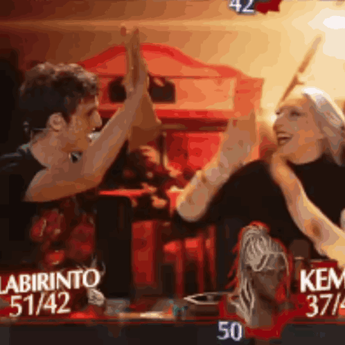 A Man And A Woman Are Giving Each Other A High Five In Front Of A Sign That Says Labirinto 51/42 GIF