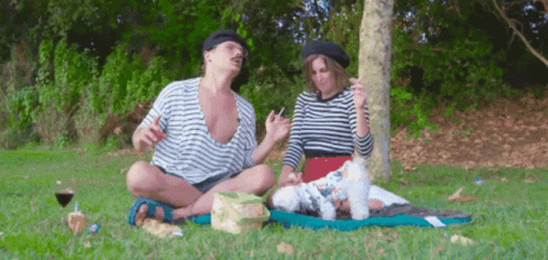 A Man And A Woman Are Having A Picnic With Their Dog GIF