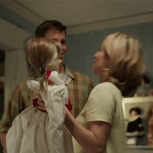 A Man And A Woman Are Holding A Little Girl Doll GIF