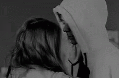 A Man And A Woman Are Hugging And Kissing In A Black And White Photo . The Woman Is Wearing A Hoodie . GIF