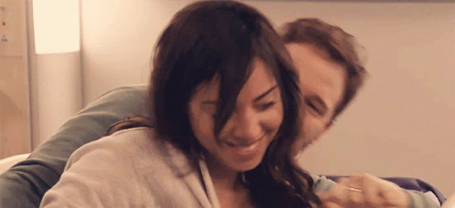 A Man And A Woman Are Hugging And Smiling GIF