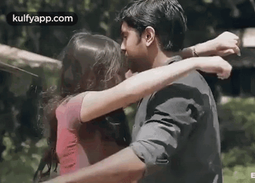 A Man And A Woman Are Hugging Each Other And Kissing . GIF