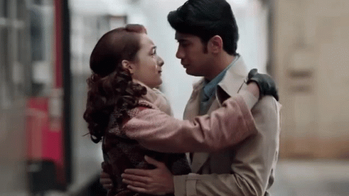 a man and a woman are hugging each other and kissing on a street .