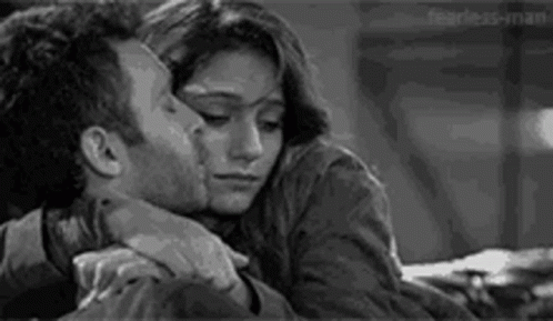 A Man And A Woman Are Hugging Each Other And Kissing . GIF