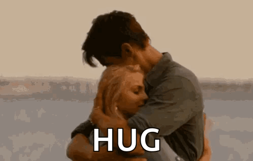 A Man And A Woman Are Hugging Each Other And The Man Is Saying `` Hug '' . GIF