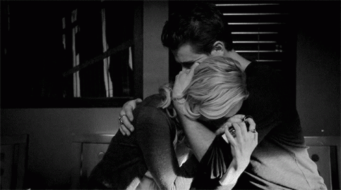A Man And A Woman Are Hugging Each Other In A Black And White Photo GIF