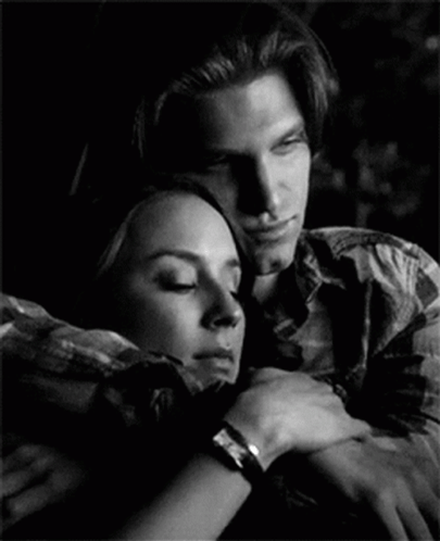 A Man And A Woman Are Hugging Each Other In A Black And White Photo GIF