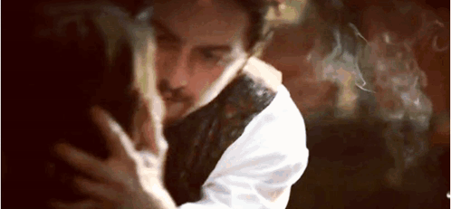 A Man And A Woman Are Hugging Each Other In A Dark Room With Smoke Coming Out Of Their Mouths . GIF
