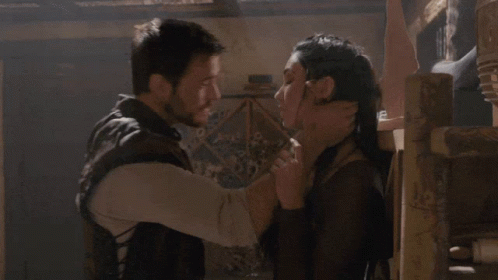 A Man And A Woman Are Hugging Each Other In A Dark Room GIF