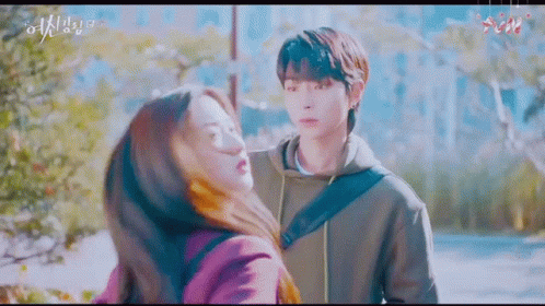 A Man And A Woman Are Hugging Each Other In A Park . GIF