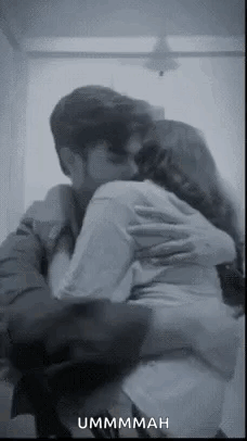 A Man And A Woman Are Hugging Each Other In A Room . GIF