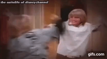 A Man And A Woman Are Hugging Each Other In A Room With Their Arms Outstretched . GIF