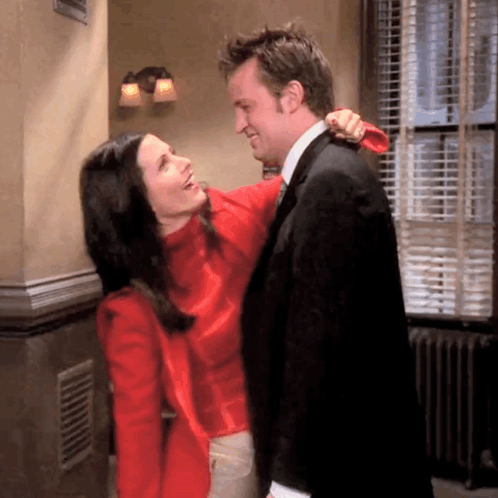 A Man And A Woman Are Hugging Each Other In A Room GIF