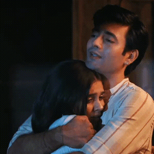 A Man And A Woman Are Hugging Each Other In The Dark . GIF